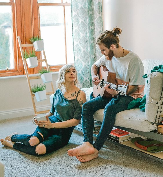 Cuplu tanar in sufragerie cantand la chitara